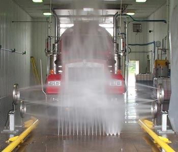 truck moving through a wash bay with jets spraying water from the floor as an undercarriage wash